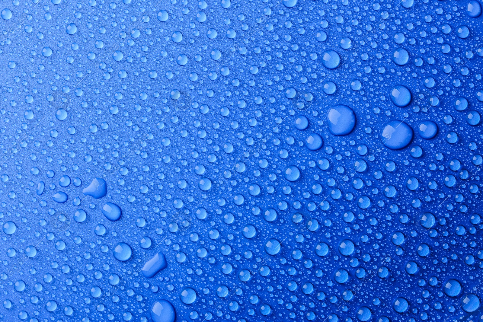 Photo of Water drops on blue background, top view