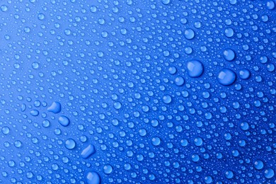 Photo of Water drops on blue background, top view