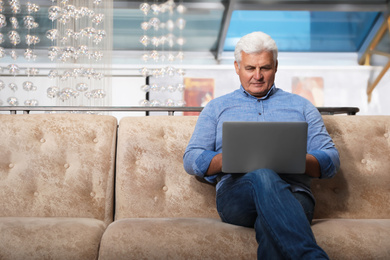 Senior business owner working with laptop in his restaurant