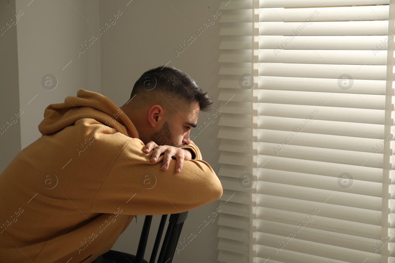 Photo of Sad man sitting on chair near window. Space for text