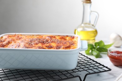 Tasty cooked lasagna in baking dish on white marble table