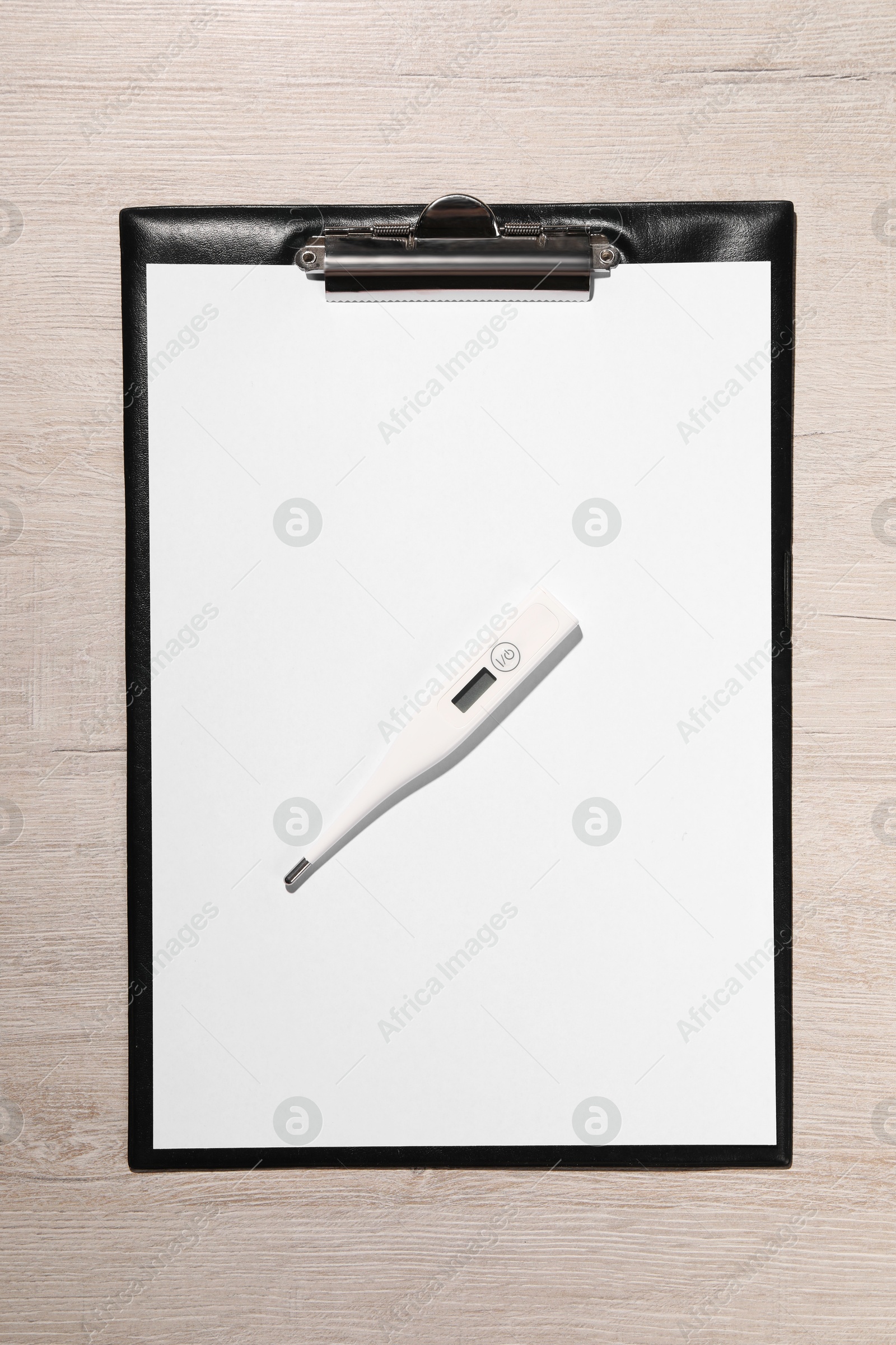 Photo of Clipboard and thermometer on wooden table, top view. Medical treatment