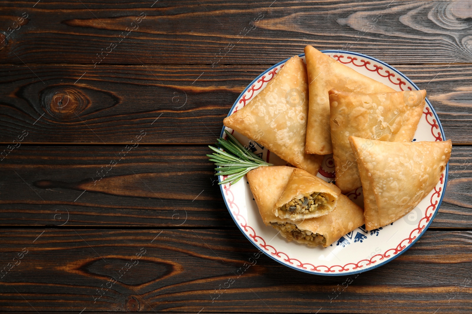 Photo of Fresh delicious crispy samosas served on wooden table, top view. Space for text