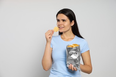Photo of Beautiful woman eating potato chips on grey background. Space for text