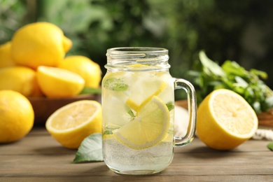 Photo of Mason jar of cold lemonade on wooden table