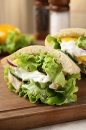 Delicious pita sandwiches with chicken breast and vegetables on wooden table, closeup