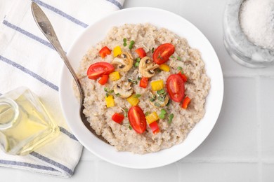 Photo of Delicious barley porridge with vegetables and microgreens in bowl served on white table, flat lay