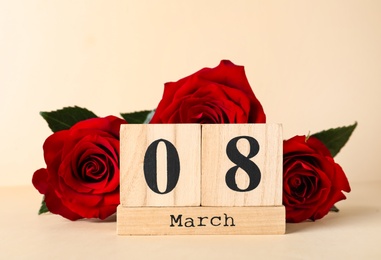 Photo of Wooden block calendar with date 8th of March and roses on beige background. International Women's Day