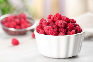 Photo of Bowl with ripe aromatic raspberries on table