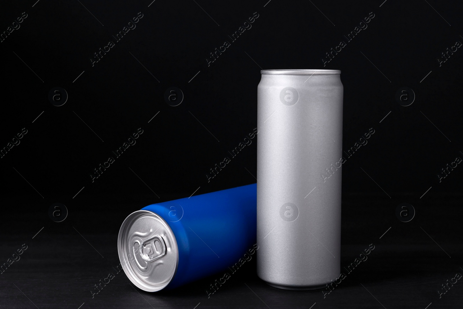 Photo of Energy drinks in cans on black wooden table