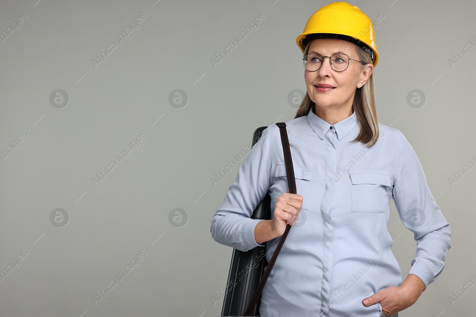 Photo of Architect in hard hat with tube on grey background, space for text