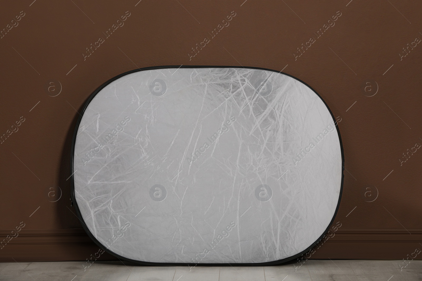 Photo of Studio reflector near brown wall in room. Professional photographer's equipment