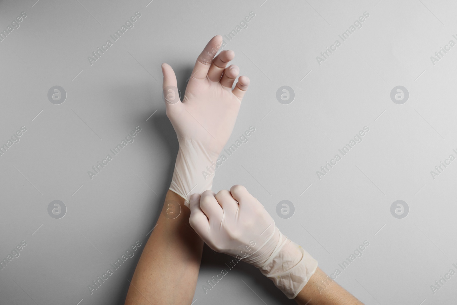 Photo of Doctor wearing white medical gloves on grey background, top view