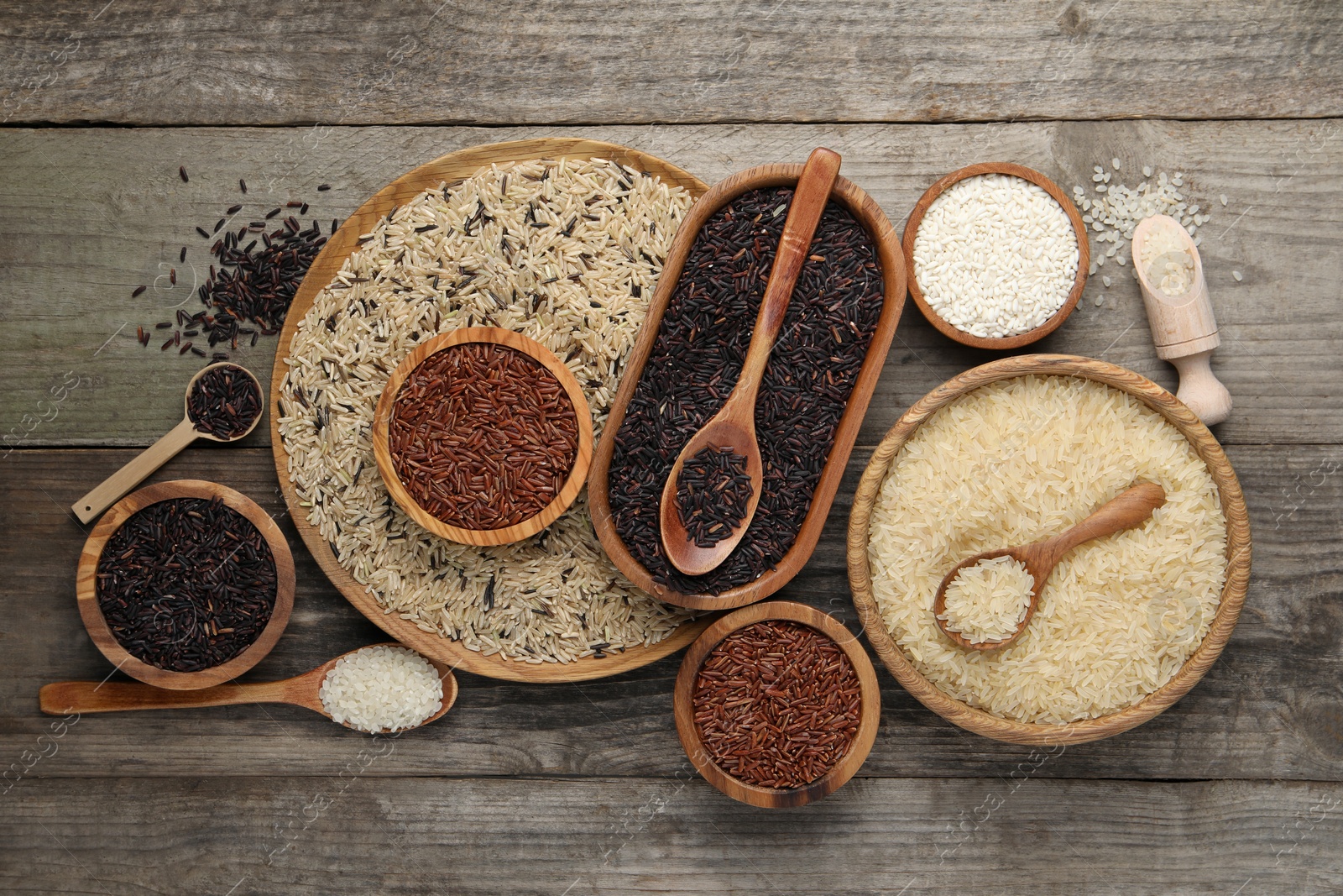 Photo of Different sorts of rice on wooden table, flat lay