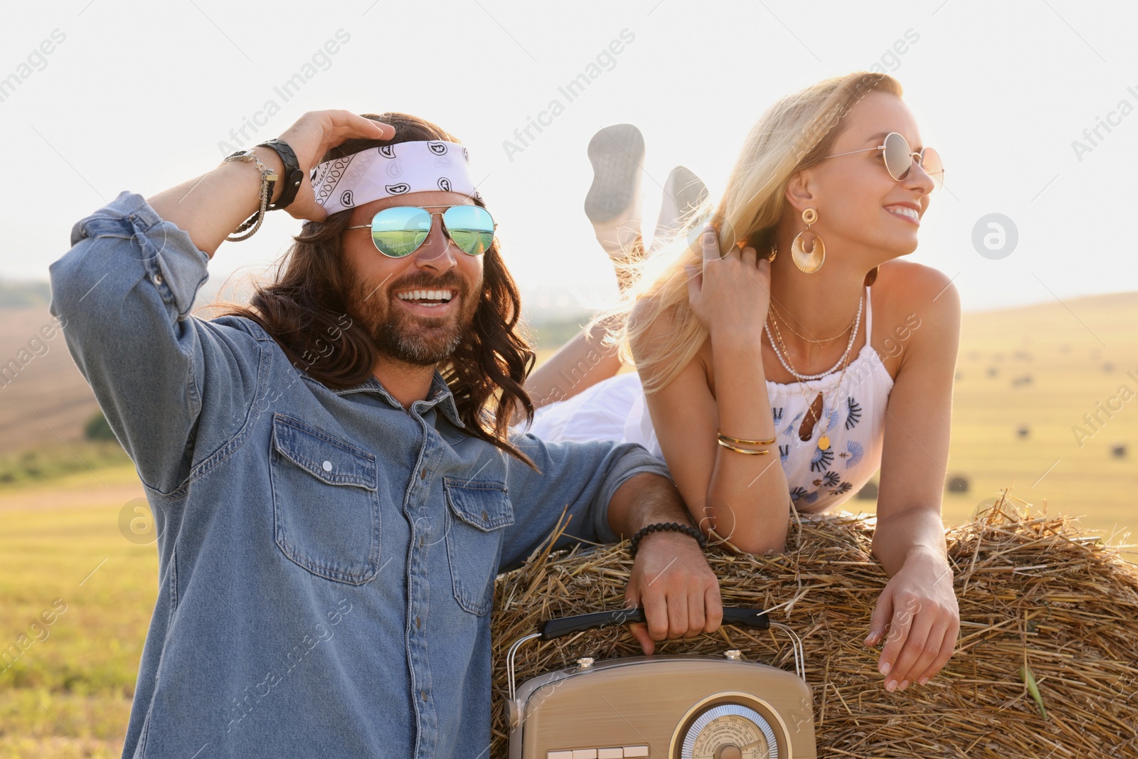 Photo of Happy hippie couple with radio receiver in field