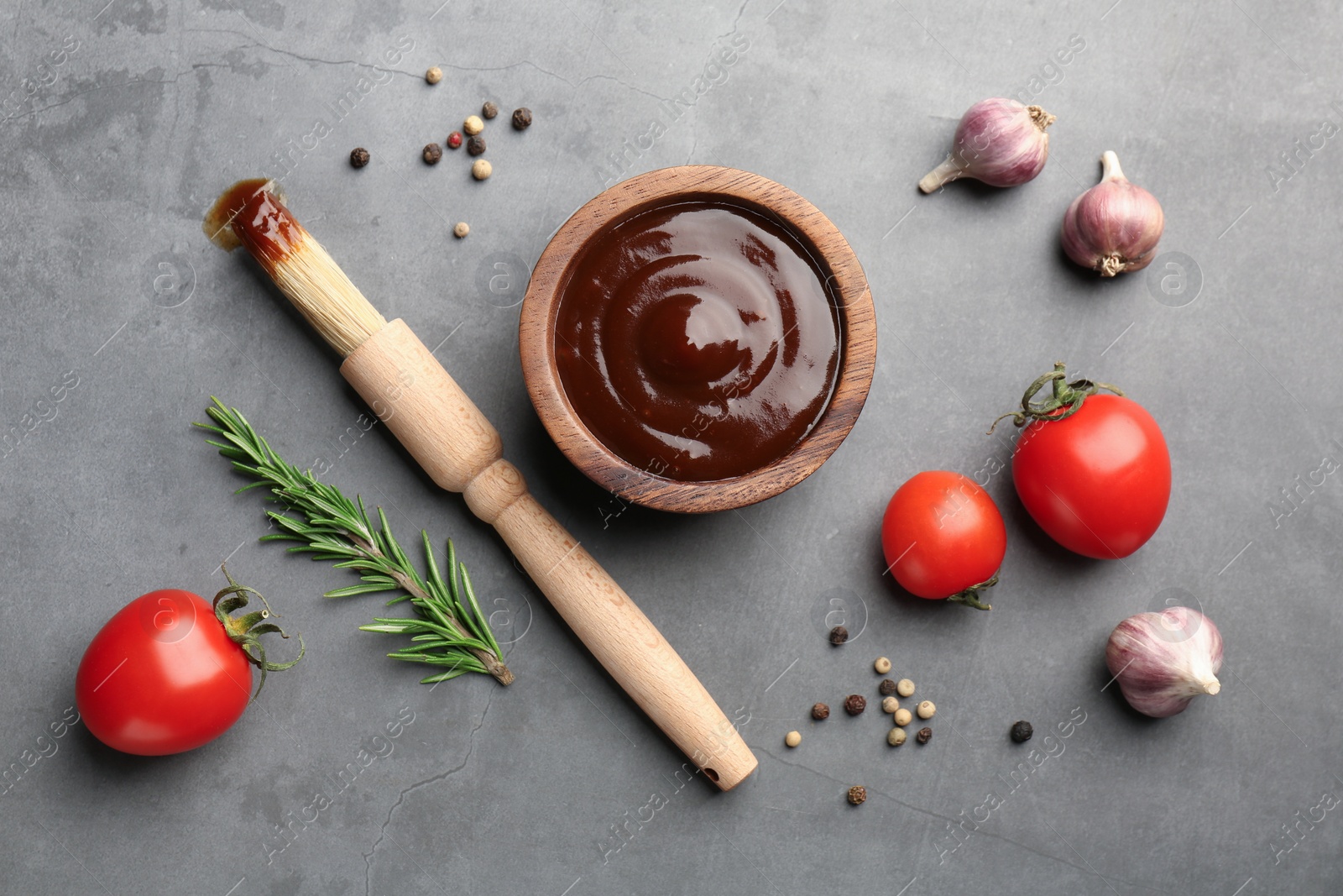 Photo of Flat lay composition with tasty barbeque sauce in bowl on grey textured table