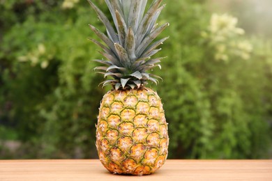 Photo of Delicious ripe pineapple on wooden table outdoors