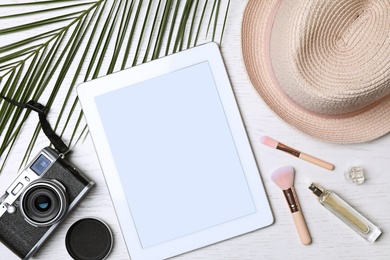 Flat lay composition with tablet and travel blogger's stuff on white wooden table, space for design