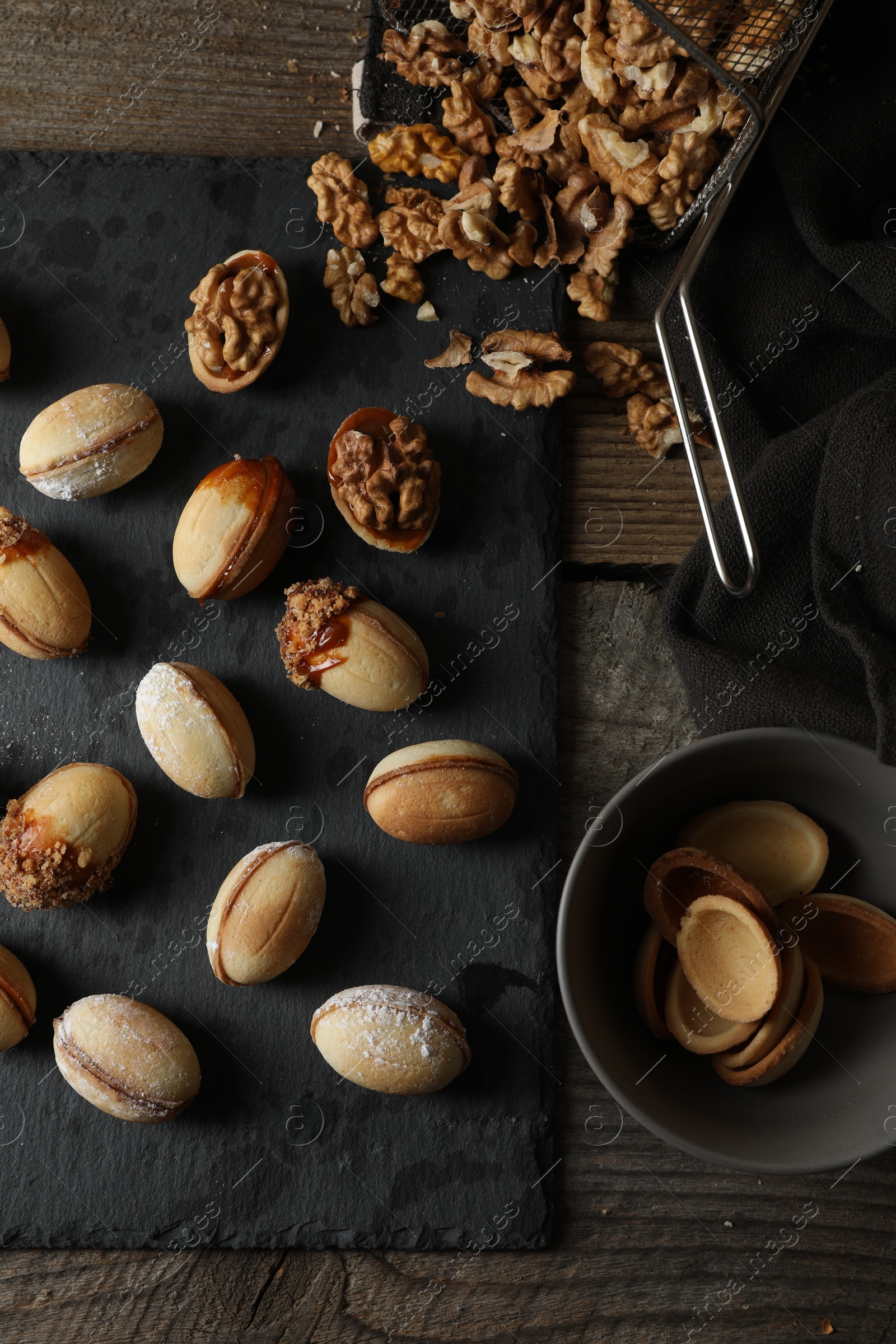 Photo of Freshly baked homemade walnut shaped cookies and nuts on wooden table, flat lay