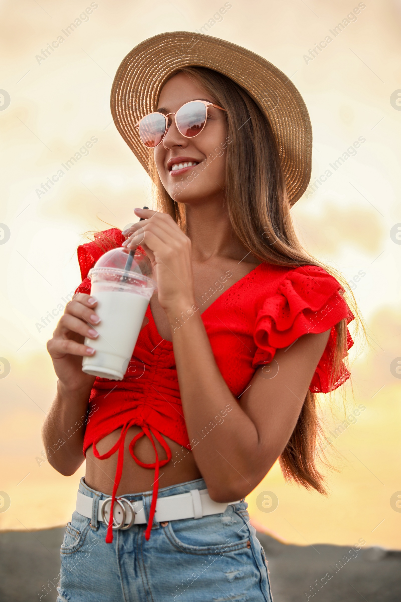 Photo of Beautiful young woman with tasty milk shake on beach