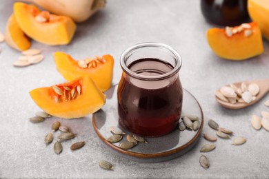 Photo of Fresh pumpkin seed oil in glass jar on grey table
