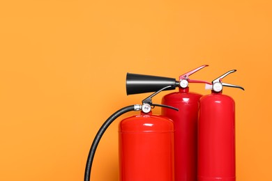 Fire extinguishers on orange background, closeup. Space for text