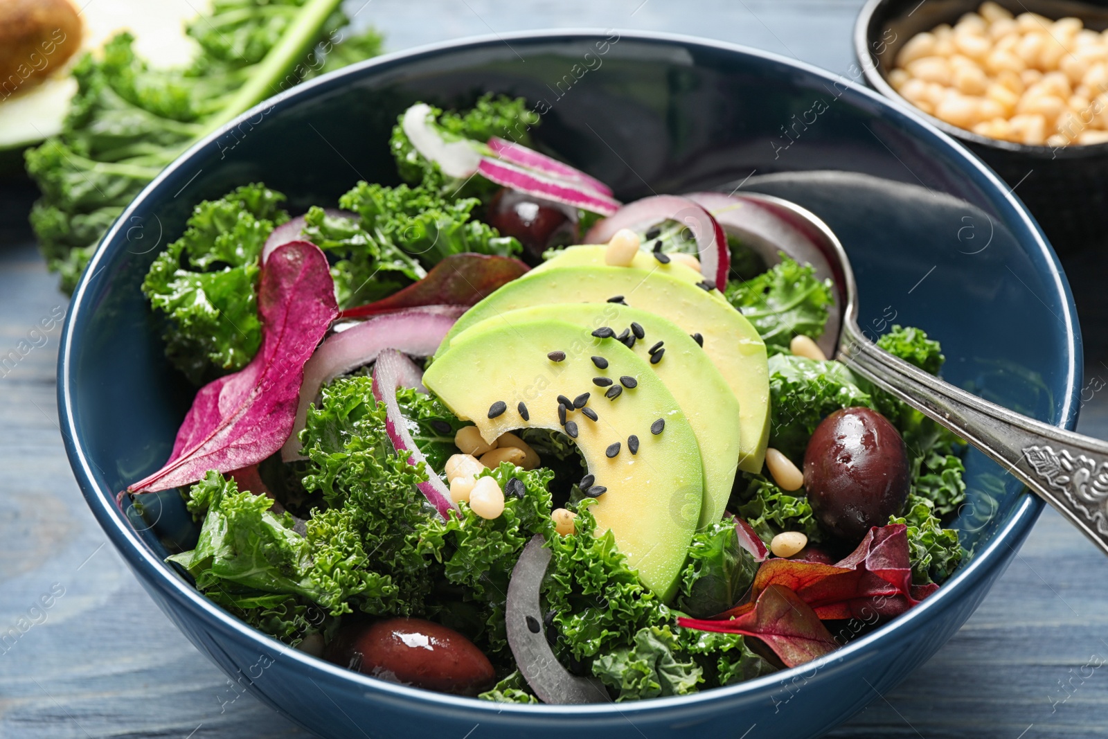 Photo of Tasty fresh kale salad on blue wooden table, closeup