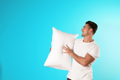 Photo of Young man with soft pillow on color background