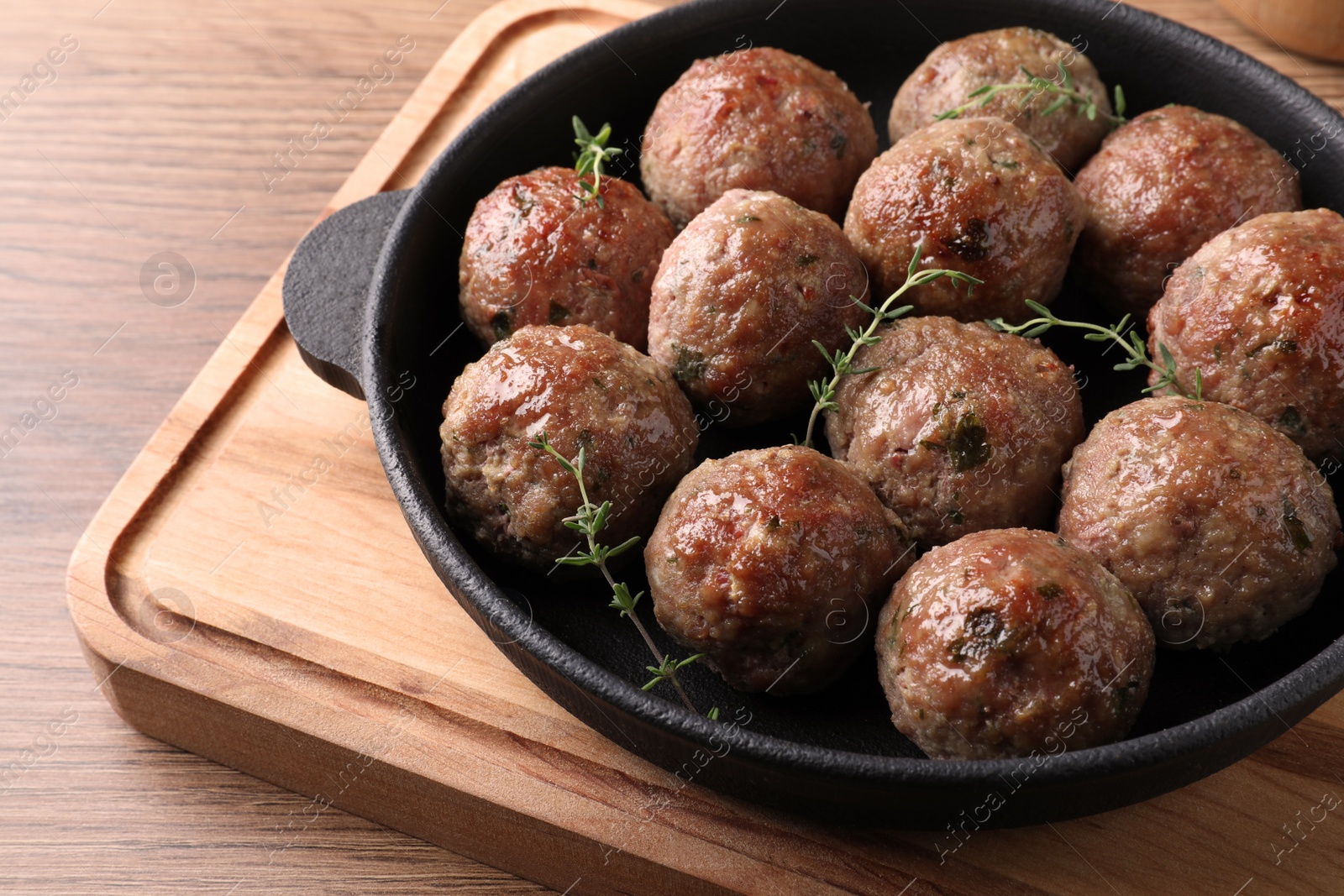 Photo of Tasty cooked meatballs served on wooden board