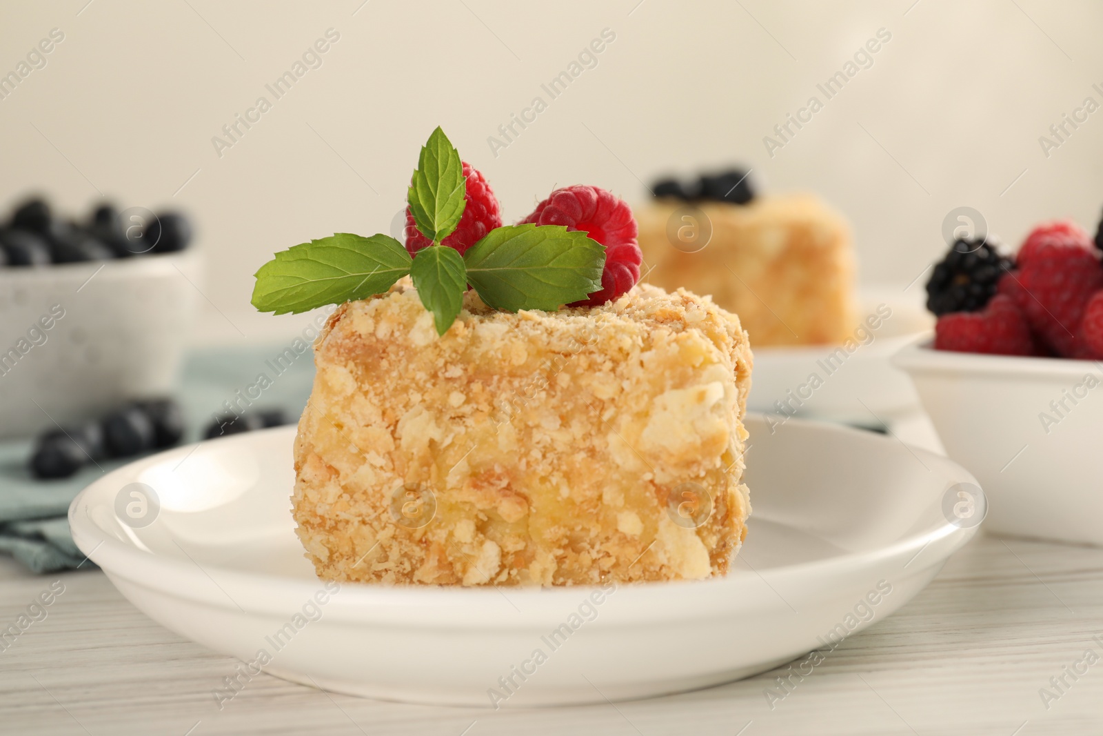 Photo of Piece of Napoleon cake with raspberries on wooden table, closeup
