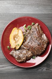 Photo of Delicious roasted beef meat, caramelized pear and thyme on grey wooden table, top view