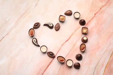 Heart made with delicious chocolate candies on marble table, top view