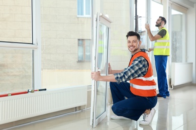 Construction workers installing plastic windows in house