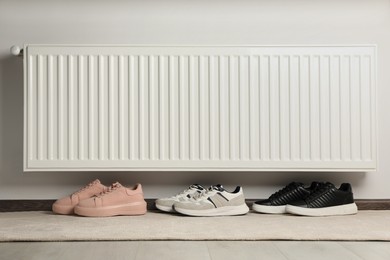 Shoes near white heating radiator in room