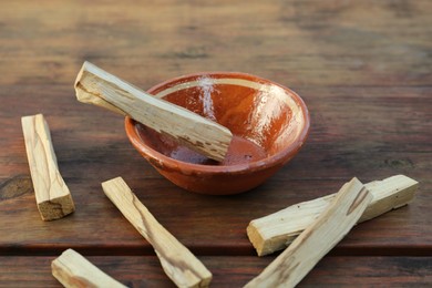 Palo santo sticks and bowl on wooden table