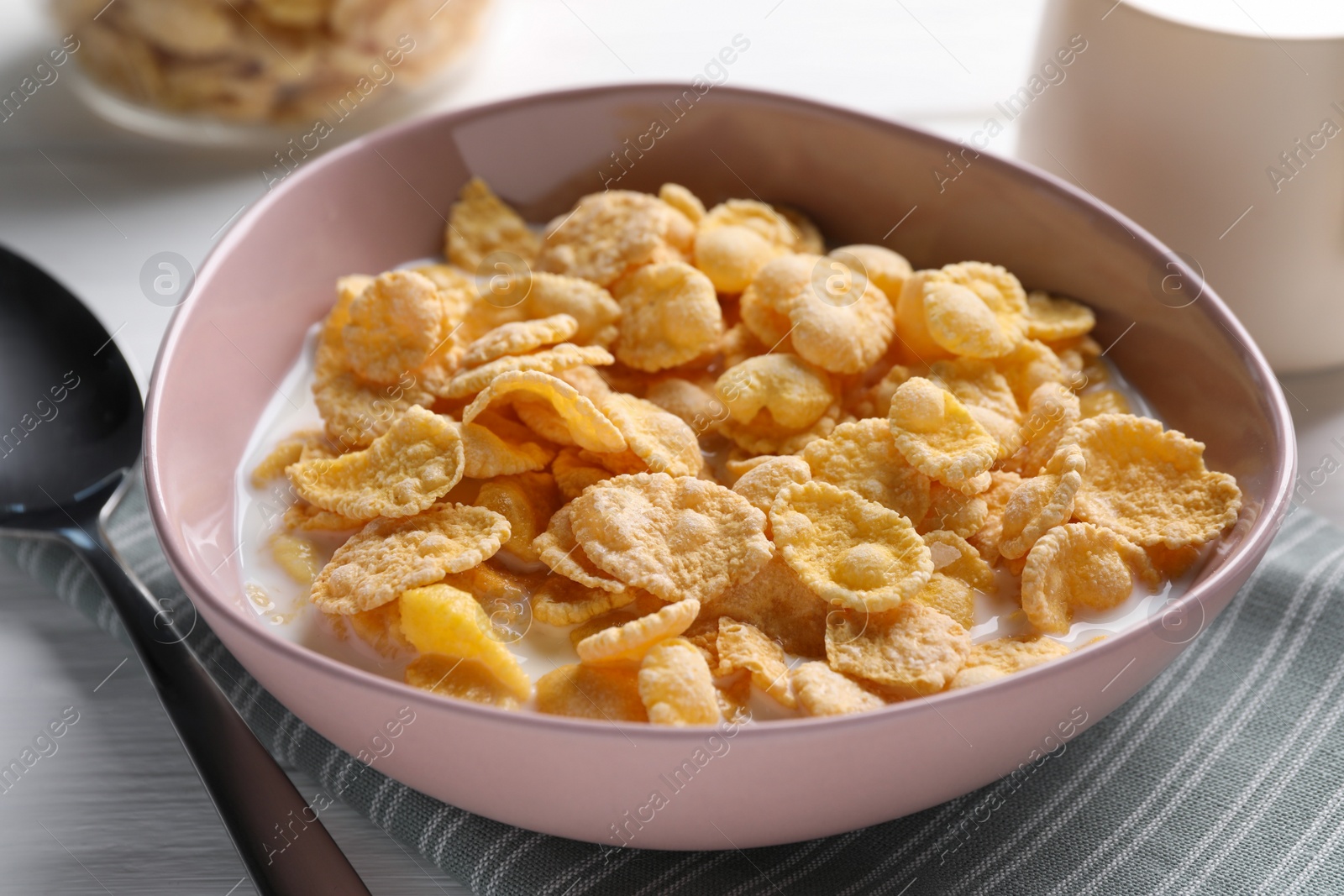 Photo of Tasty cornflakes with milk in bowl on table, closeup