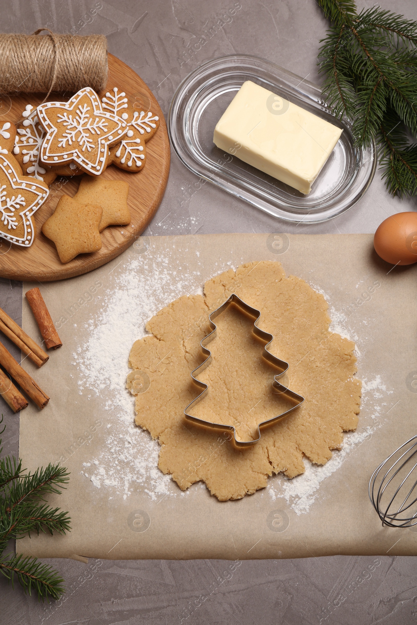 Photo of Making Christmas cookies. Flat lay composition with ingredients and raw dough on grey table