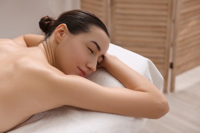 Photo of Beautiful woman relaxing on massage couch in spa salon, space for text