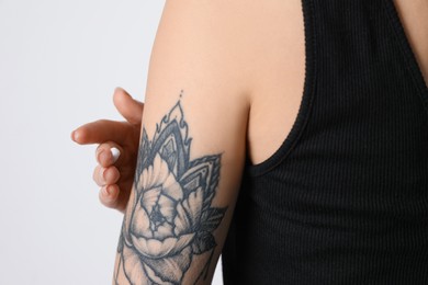 Photo of Woman applying cream onto her arm with tattoo on white background, closeup