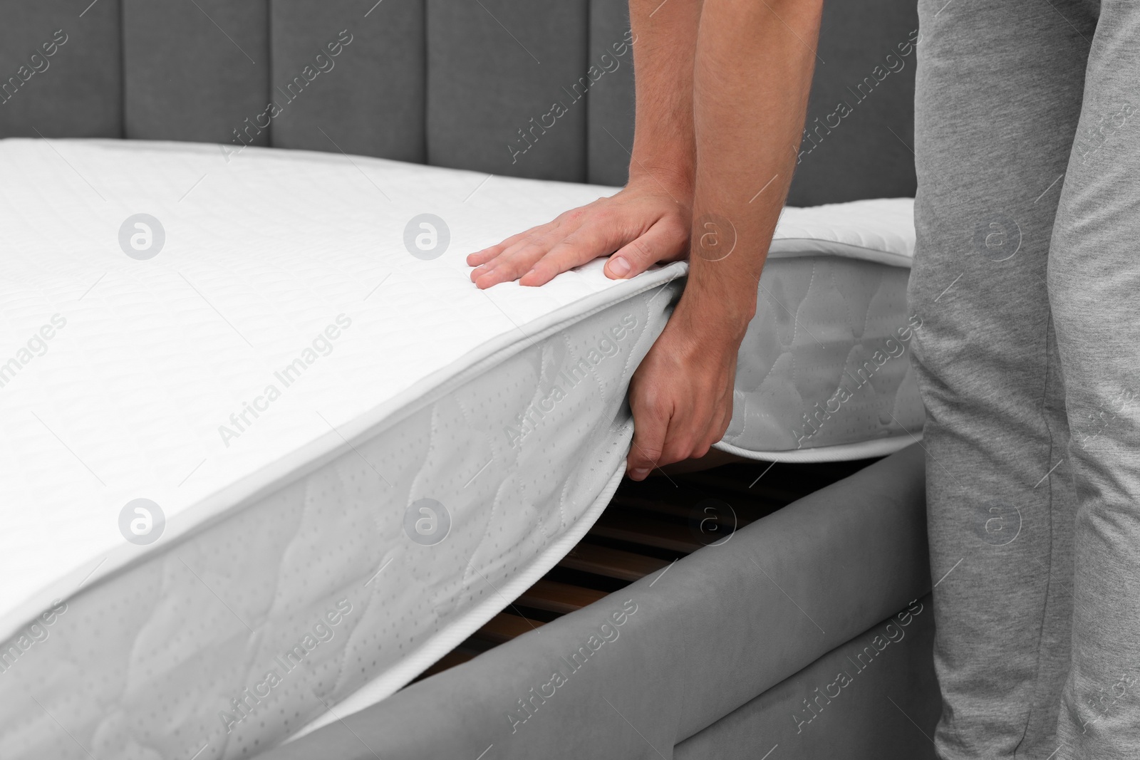 Photo of Man putting soft mattress on bed, closeup