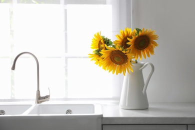 Photo of Bouquet of beautiful sunflowers on counter in kitchen