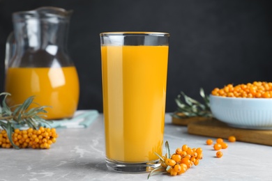 Photo of Sea buckthorn juice and fresh berries on white marble table, closeup