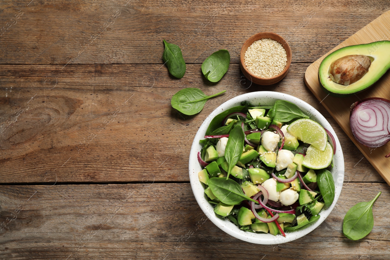 Photo of Delicious avocado salad with mozzarella on wooden table, flat lay. Space for text