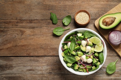 Delicious avocado salad with mozzarella on wooden table, flat lay. Space for text