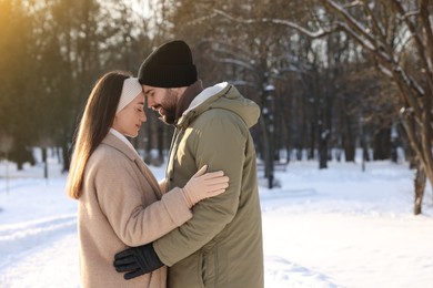 Beautiful happy couple in snowy park on winter day