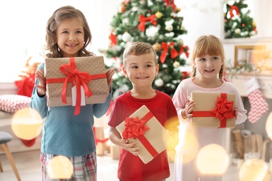 Photo of Cute little children with Christmas gift boxes at home