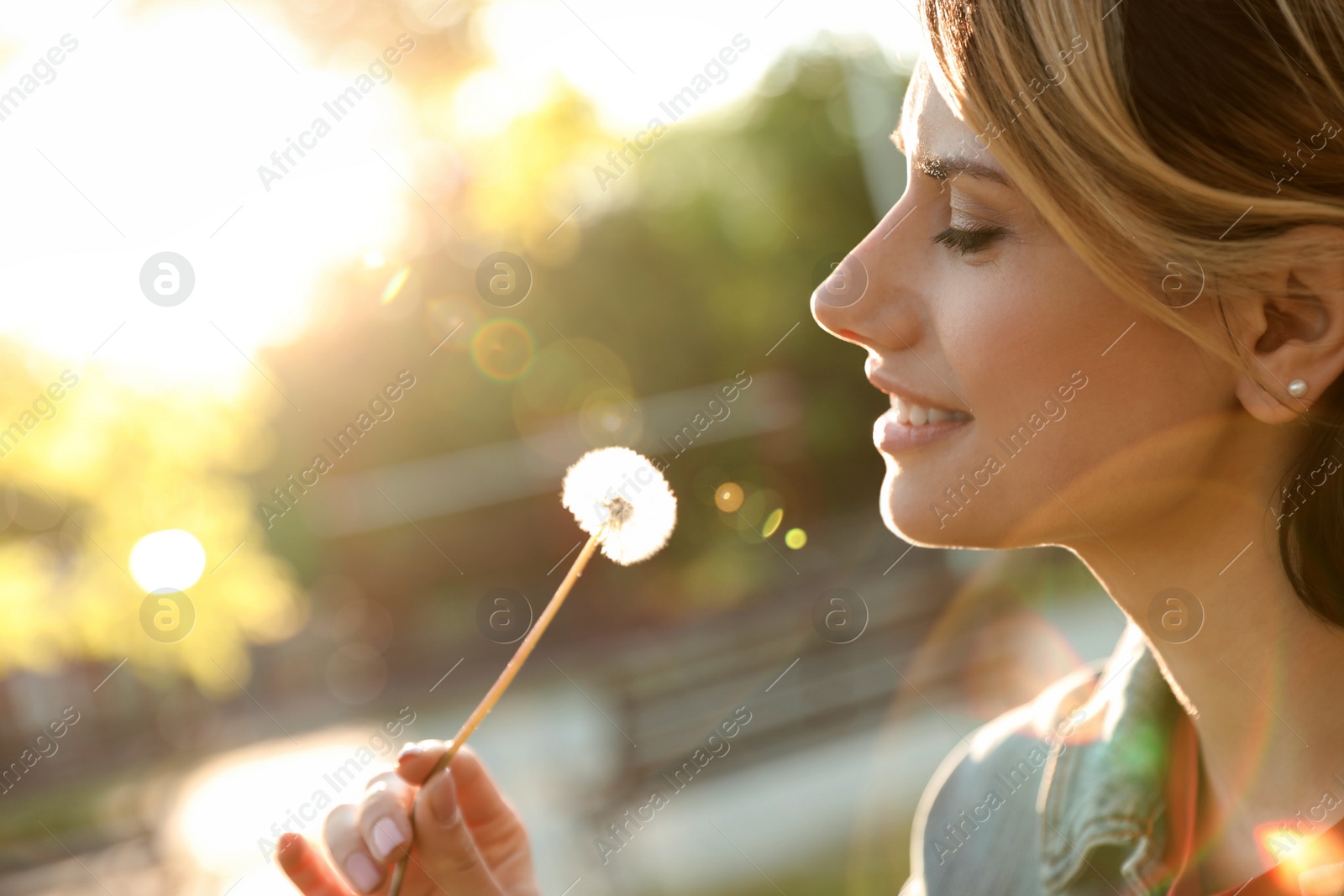 Photo of Young woman with dandelion in park on sunny day. Allergy free concept