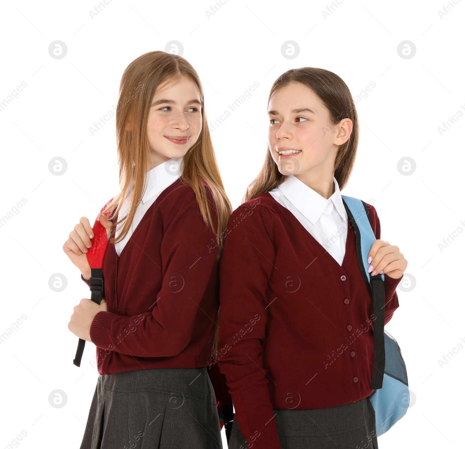 Photo of Portrait of teenage girls in school uniform with backpacks on white background