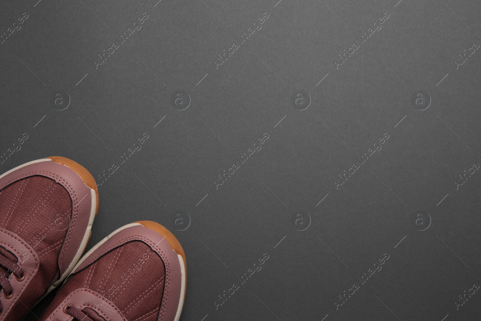 Photo of Pair of stylish kid's sneakers on black background, top view. Space for text