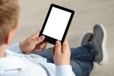 Man using e-book reader indoors, closeup view